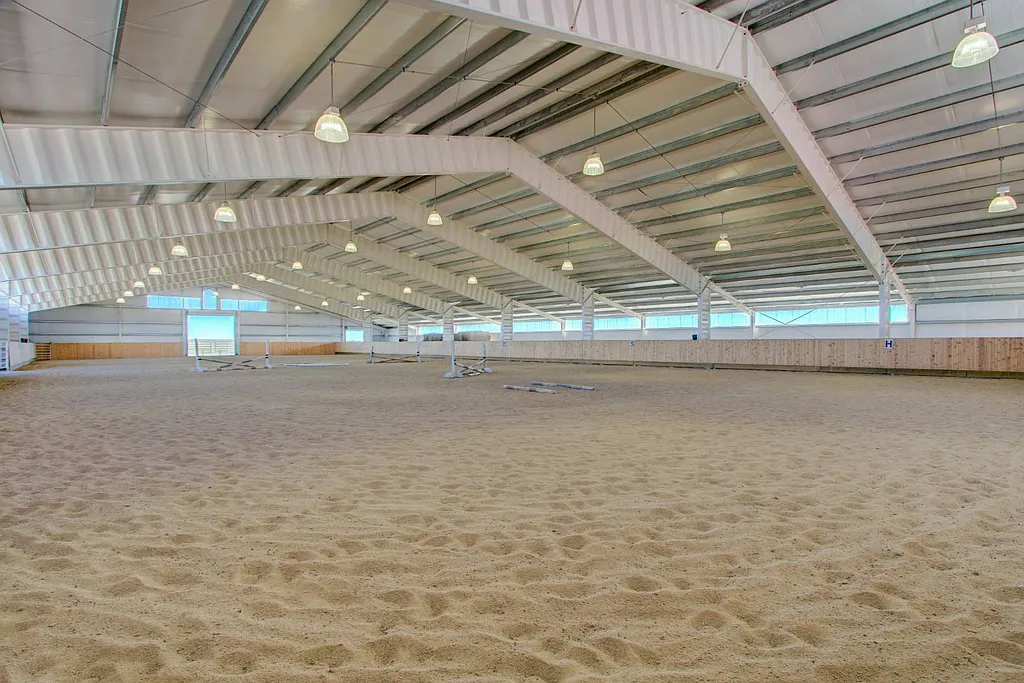 A large indoor arena with sand and white walls.